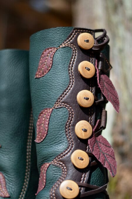 These custom green leather boots feature brown button closures and decorative maroon leaves stitched on the sides, offering you unique style options.